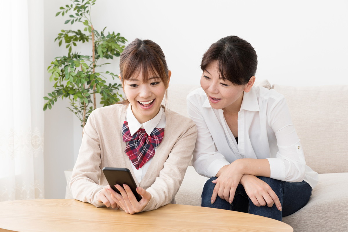 スマホを一緒に見ている女子学生と女性